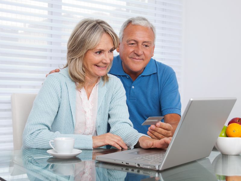 An older couple accessing a computer and smiling